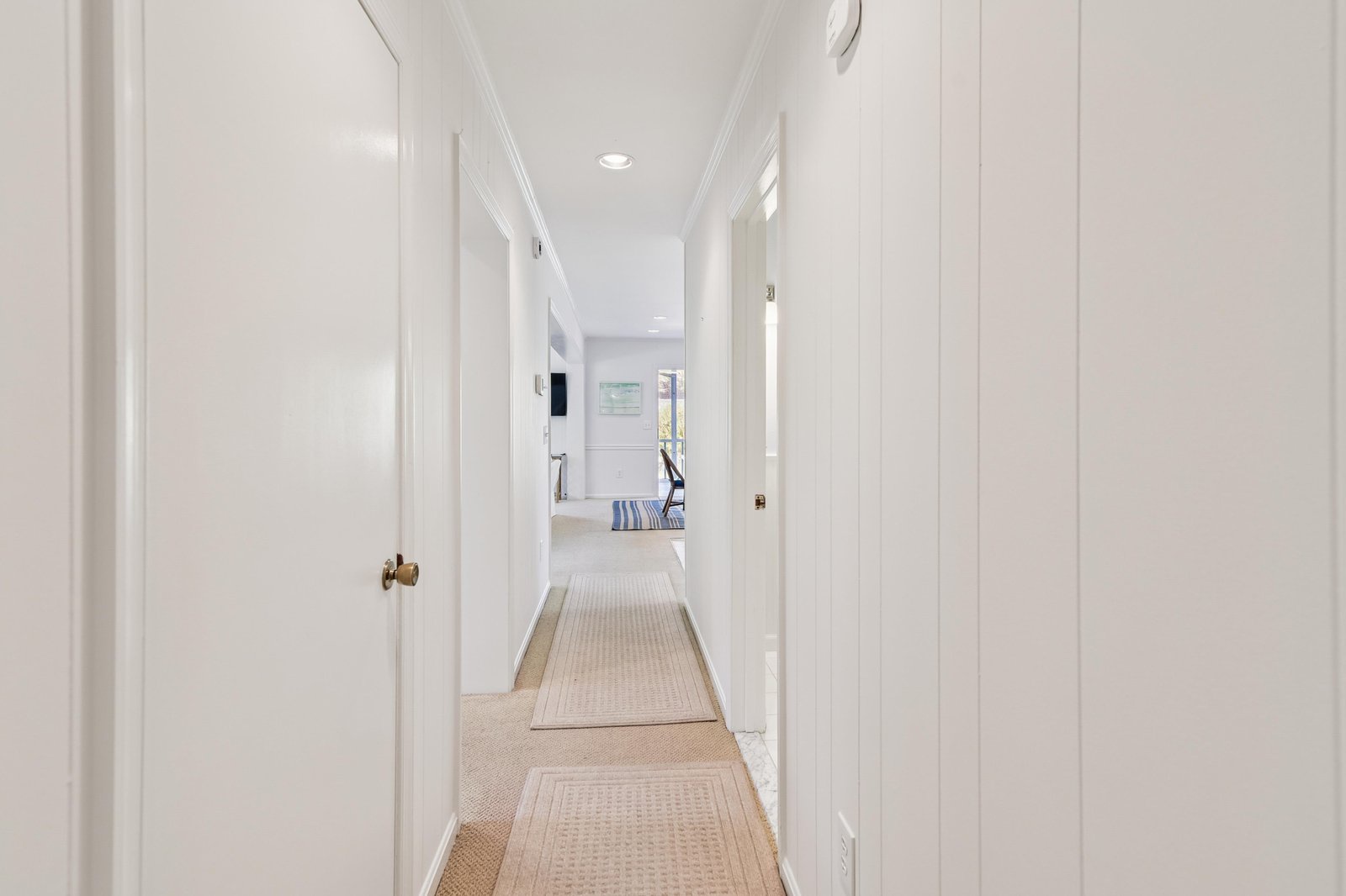 Crisp white walls and warm woven rugs guide you through this bright hallway toward your peaceful retreat—a space designed to feel like home from the moment you arrive.