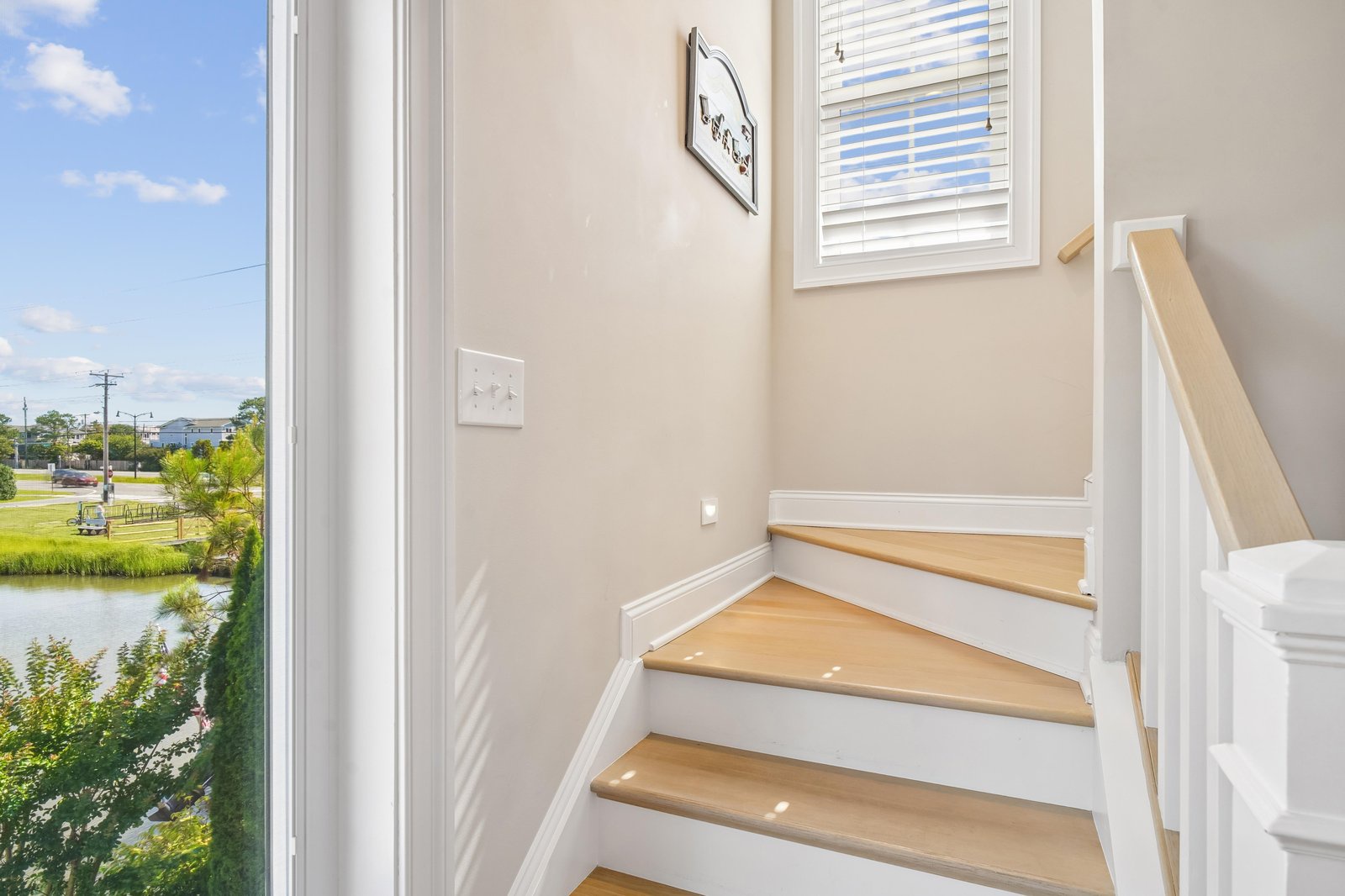 Sunlit stairway with bright windows overlooking peaceful water views, bringing natural light into your vacation retreat.