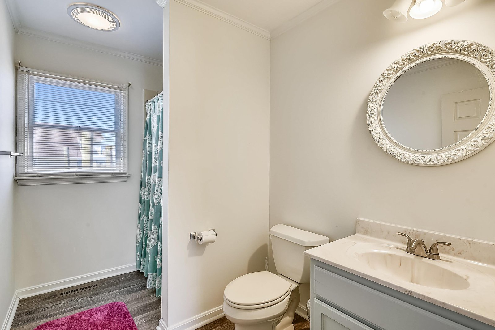 Step into your private bathroom featuring elegant marble countertops, a beautifully framed mirror, and fresh natural light streaming through the window—a serene space to refresh and unwind.