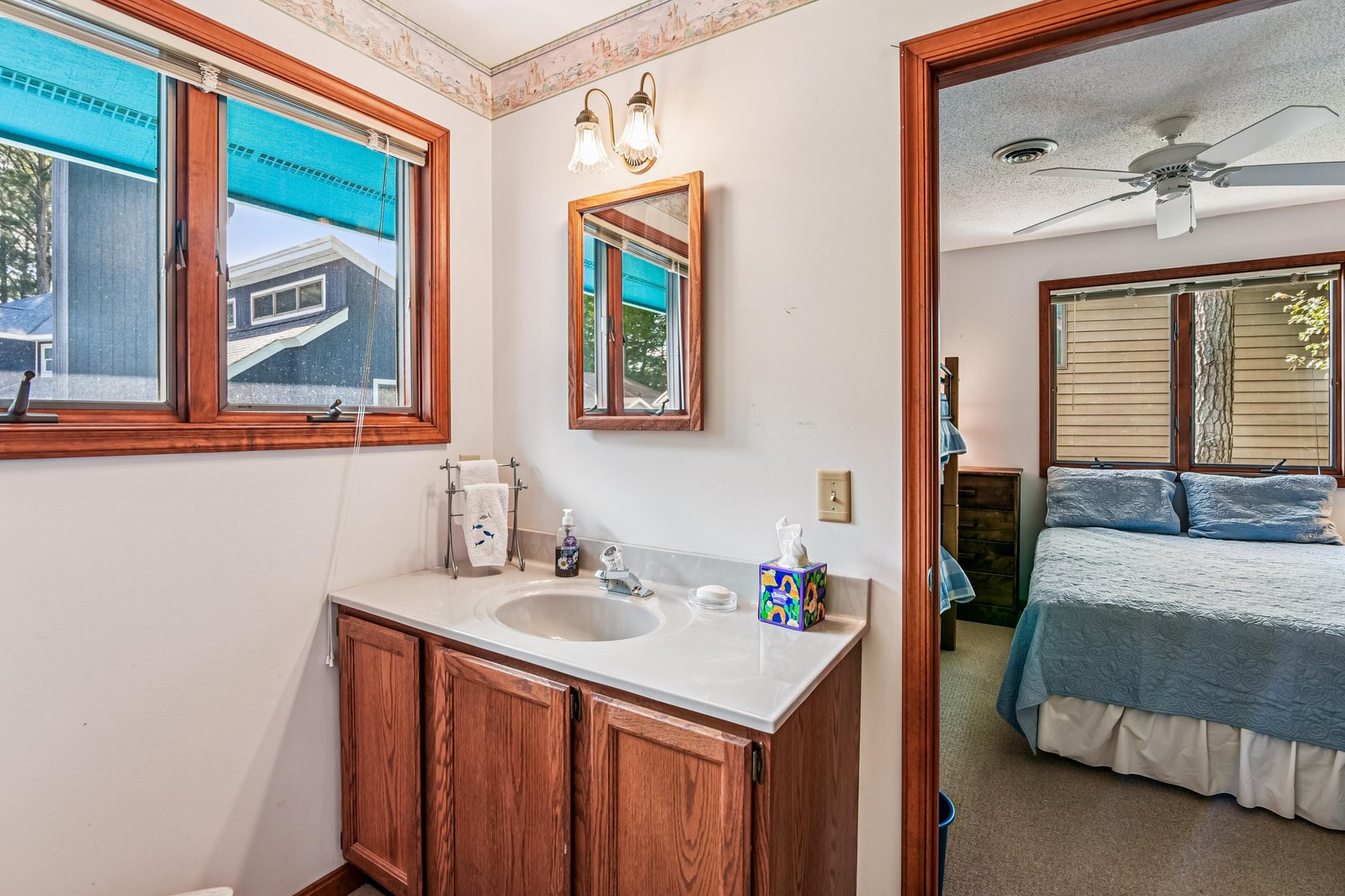 Step into your private bathroom, complete with a charming vanity and warm wood accents. Natural light from the window brightens your morning routine, while the adjoining bedroom awaits just steps away.