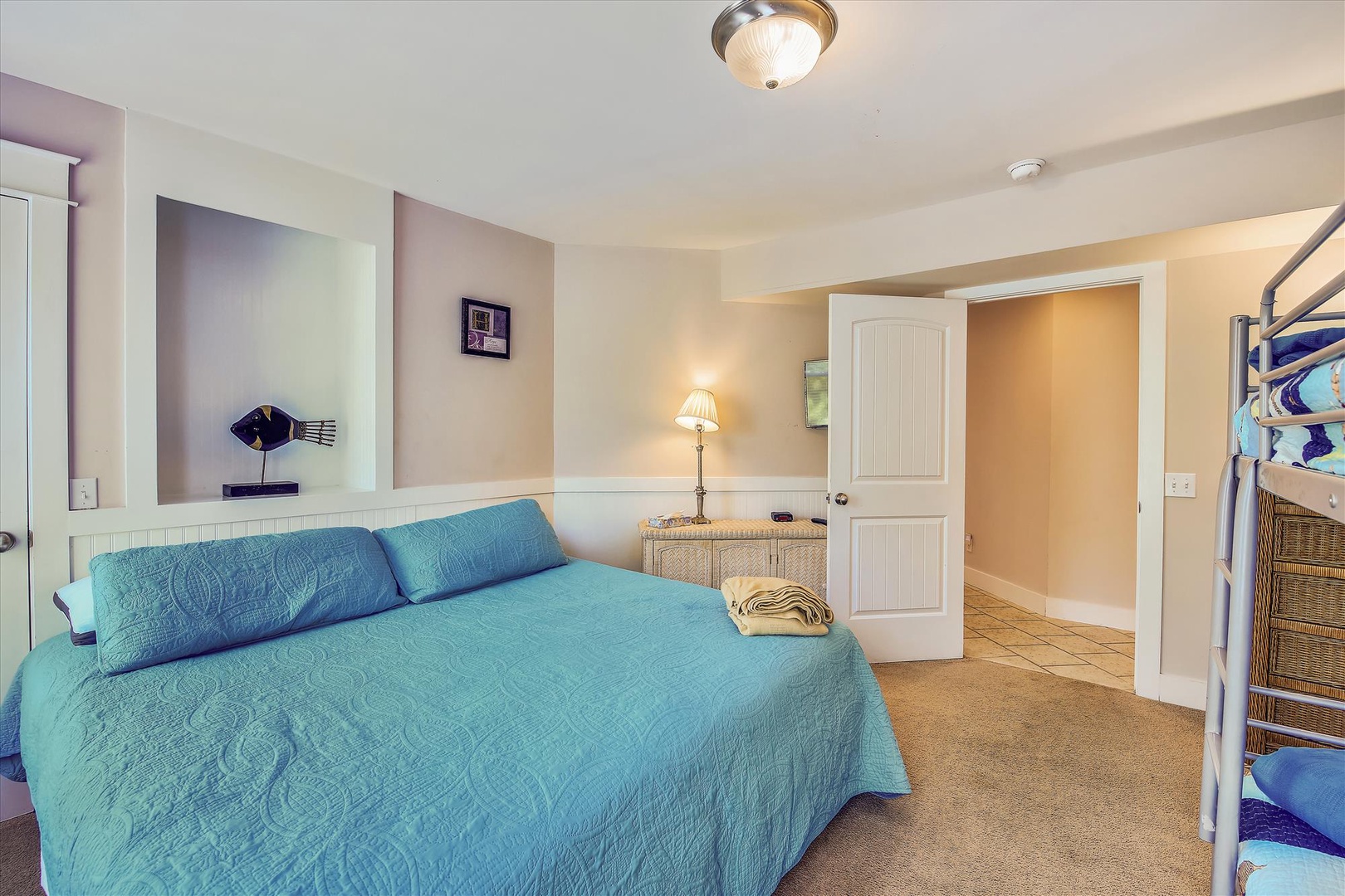 Drift off in this bright, inviting bedroom with a plush queen bed, coastal-inspired décor, and soft lighting. Your private ensuite awaits through the open door for ultimate convenience.