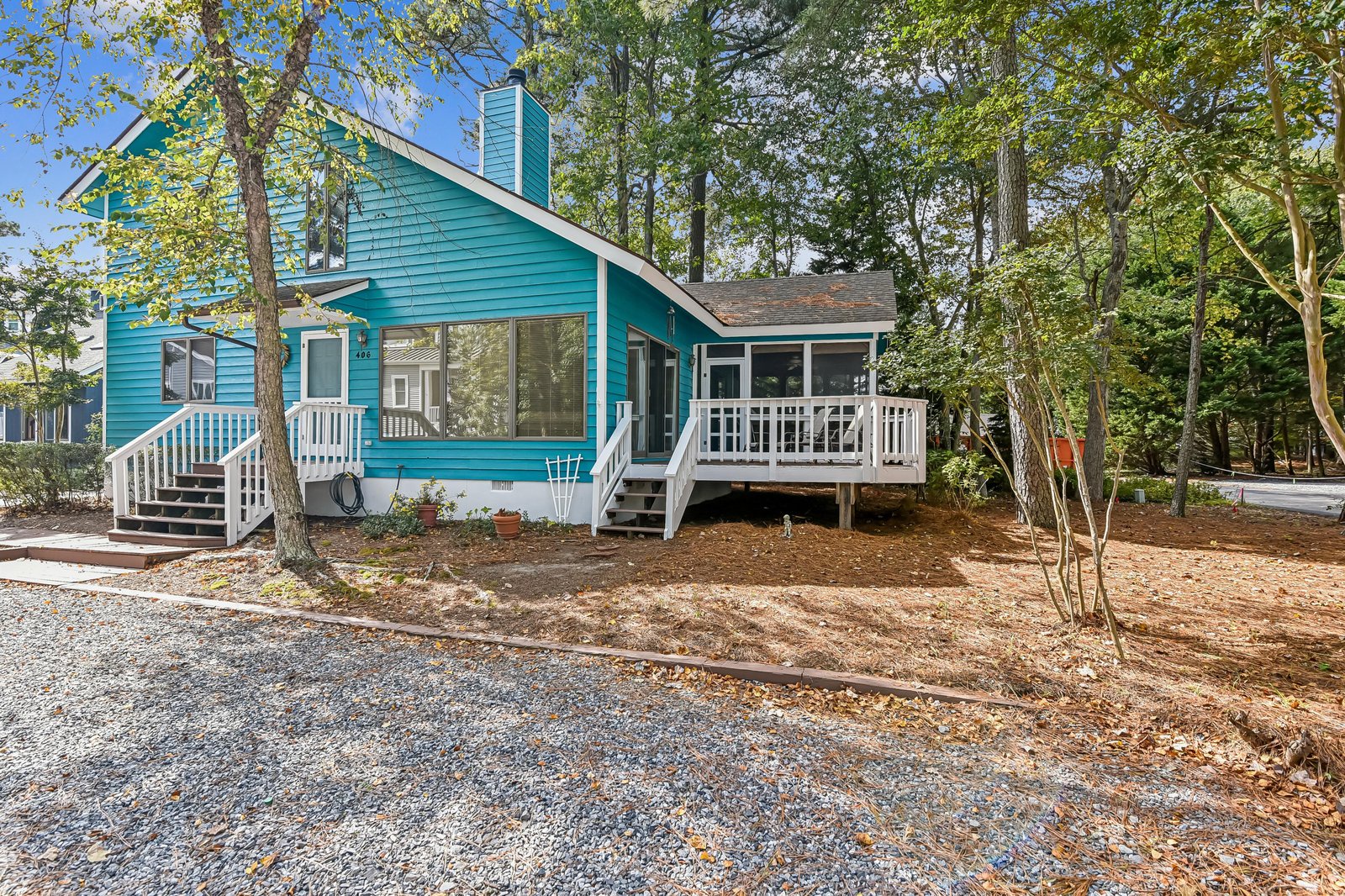 This charming teal cottage sits nestled among towering trees, with a sunny deck and screened porch where you can sip your morning coffee surrounded by nature.