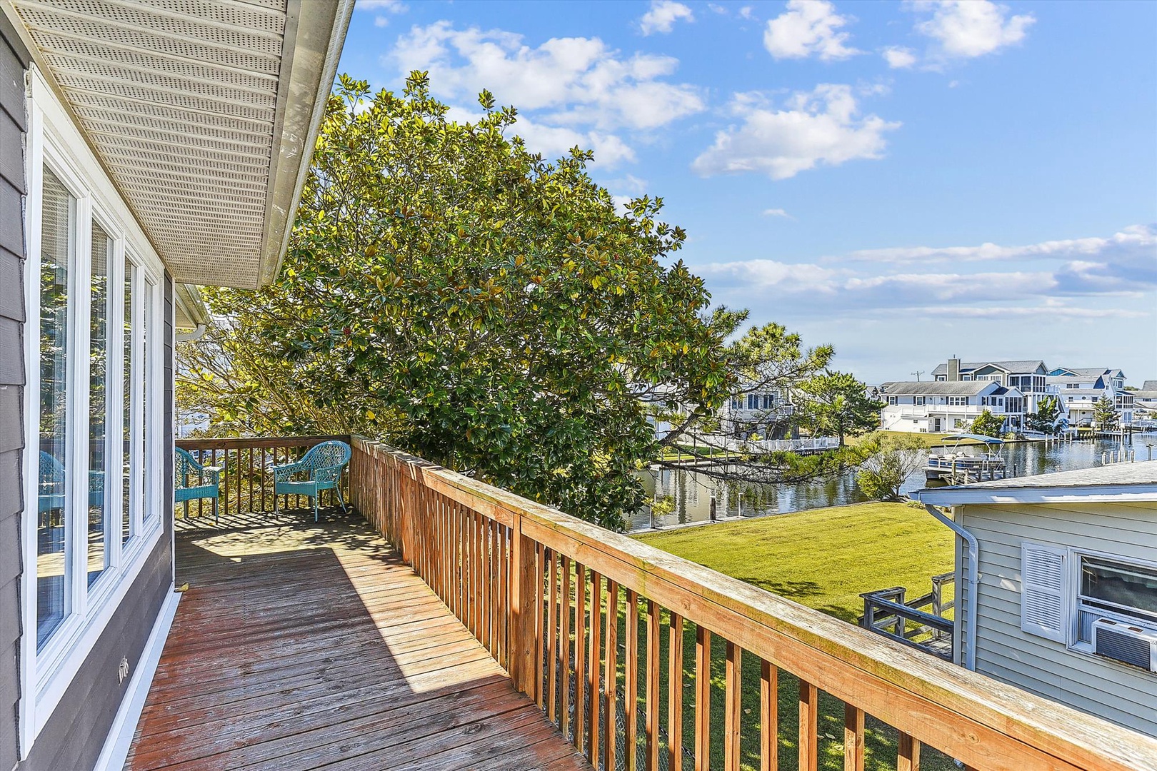 Scenic waterfront deck overlooking a tranquil canal and neighboring homes, perfect for morning coffee or evening relaxation in a peaceful coastal setting.