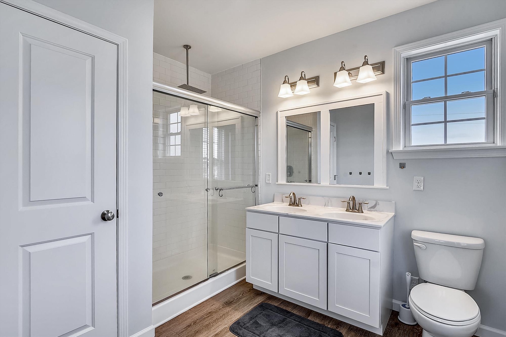 Step into your freshly renovated bathroom where bright subway tiles, dual vanities, and a spacious walk-in shower await your morning routine.