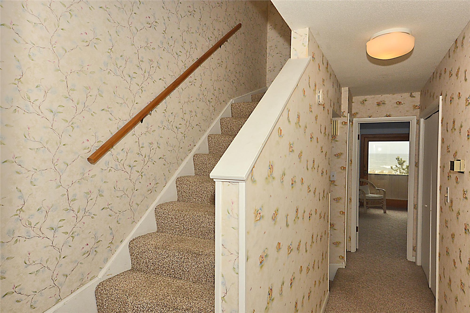 Step into your cozy retreat, where delicate floral wallpaper and soft carpeting welcome you upstairs to comfortable, inviting spaces designed for relaxation.