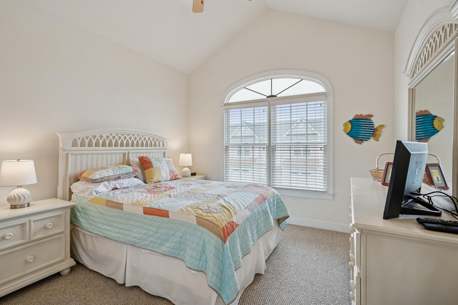 Wake up to soft natural light streaming through arched windows in this serene, beach-themed bedroom. The coastal décor and comfortable linens create your perfect retreat.