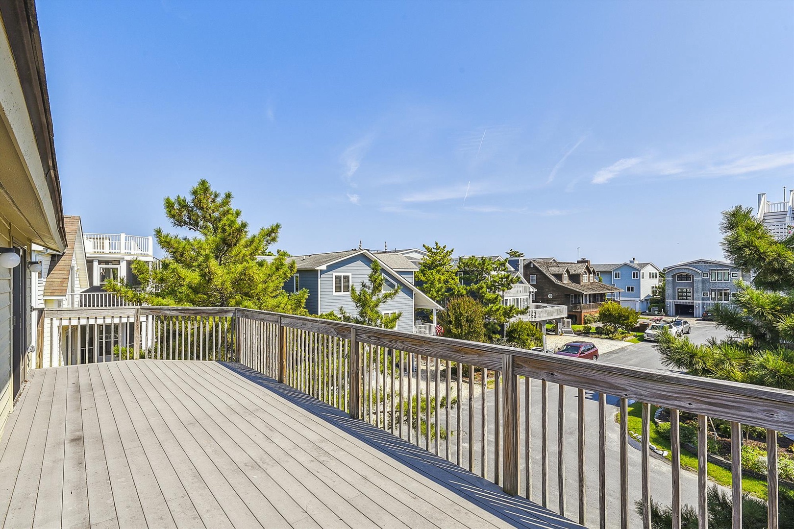 Spacious deck with neighborhood views situated in a coastal residential area with mature trees and nearby homes.