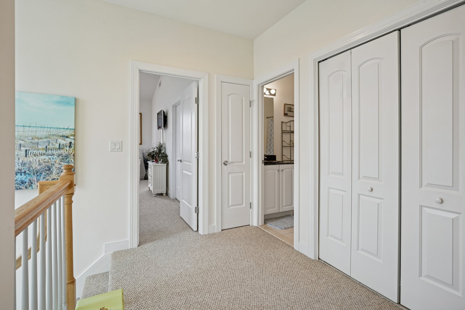 Step into your bright hallway where coastal artwork and soft carpeting create a welcoming transition to your private spaces.