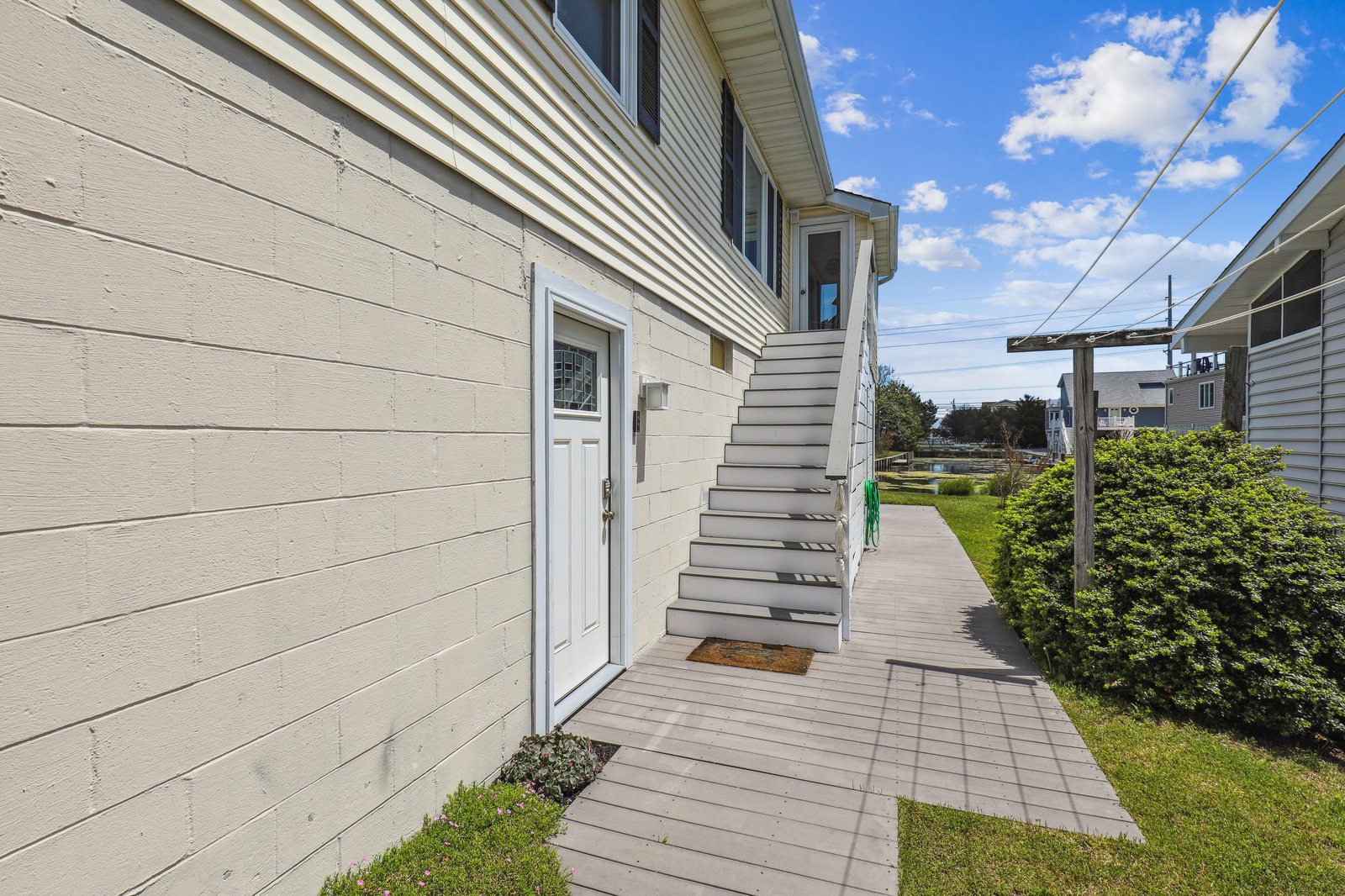 The side entrance leads to a peaceful residential neighborhood, with a sunny day highlighting the property's inviting exterior and quiet surroundings.