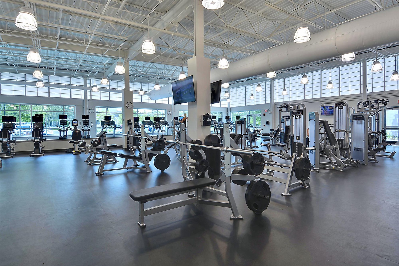A bright, spacious fitness center awaits with professional-grade equipment and natural light streaming through floor-to-ceiling windows, creating an energizing atmosphere for your daily workouts.