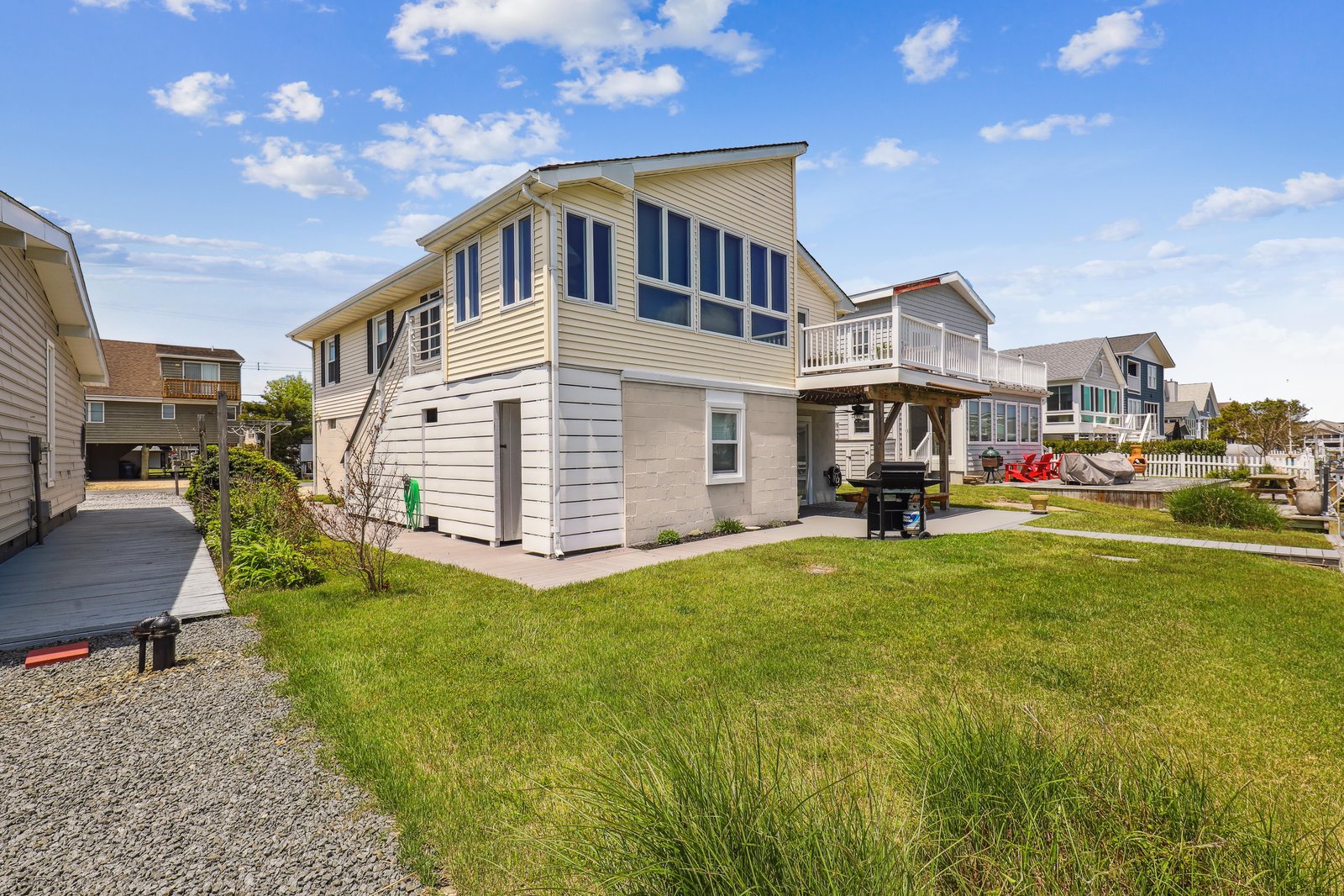 A coastal retreat with spacious lawn, elevated deck, and bright windows overlooking a friendly residential neighborhood—perfect for family beach getaways.