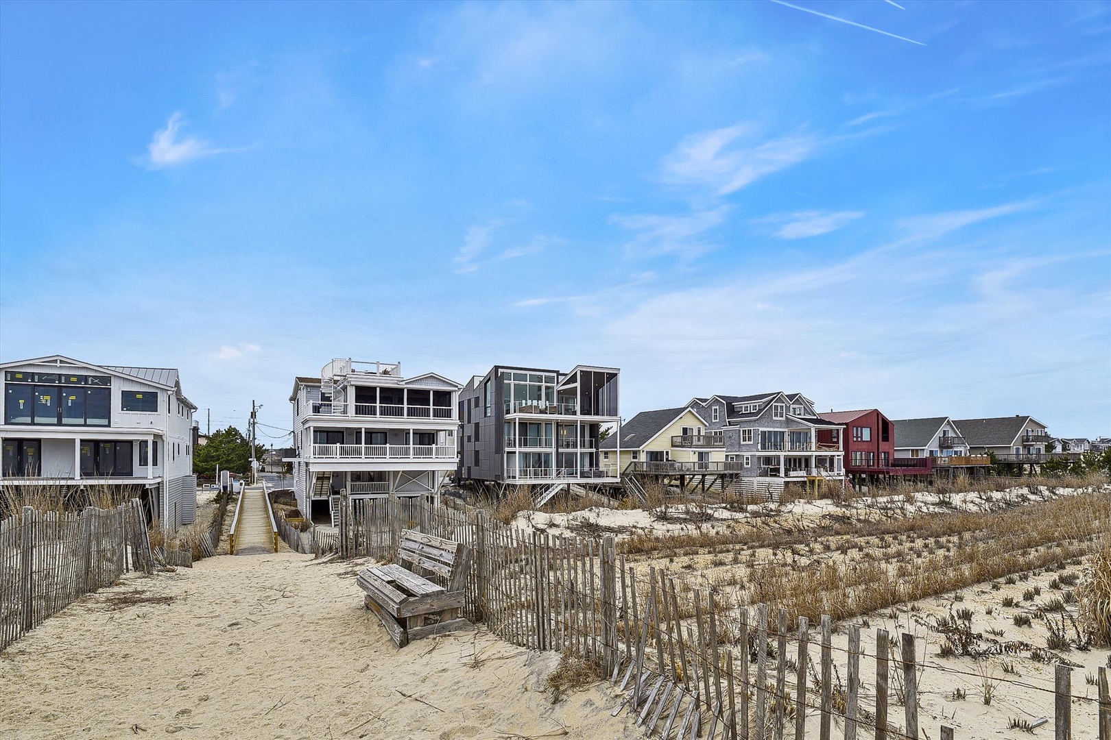 Beachfront properties line the sandy shore, offering direct access to the coast through dune-protected pathways in a charming coastal neighborhood.