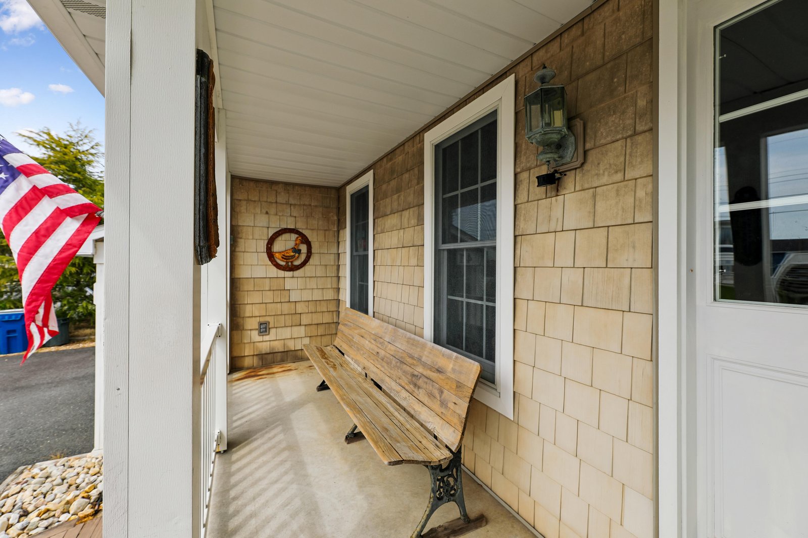 This welcoming front porch greets you with classic coastal charm, featuring a wooden bench and nautical touches perfect for your arrival.
