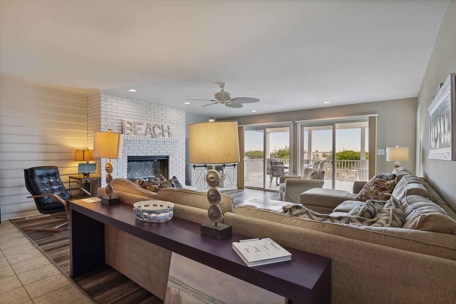 Sink into plush sofas and watch sunlight pour through the glass doors, where your private balcony awaits with beach views just beyond.