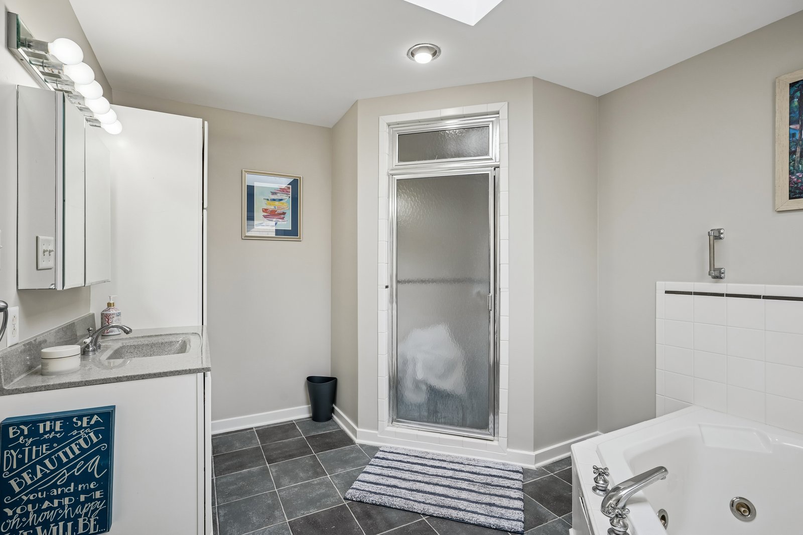 Unwind in your spacious bathroom featuring a deep soaking tub, walk-in shower, and skylight that fills the space with natural light.