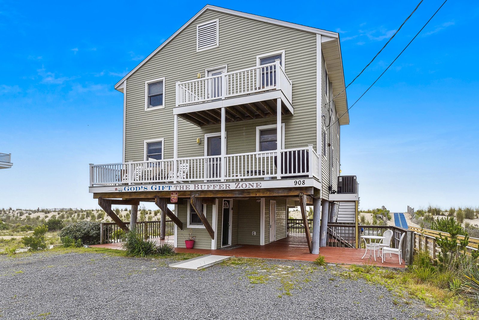 This elevated beachfront property stands ready to welcome guests with its multi-level design, spacious decks, and direct access to the sandy shores just beyond the natural dunes.