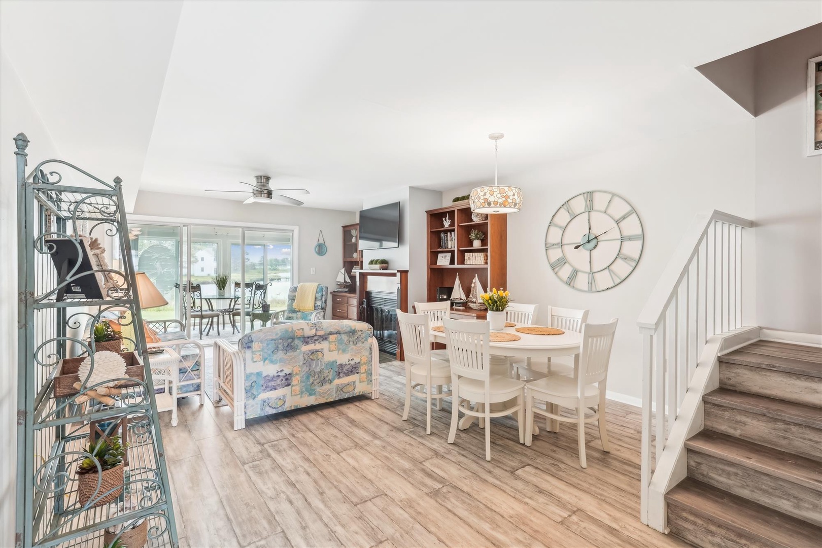 Bright, open living space flows seamlessly from dining to living room, inviting you to relax in coastal-inspired charm. Sunlight pours through large windows, warming wood floors and highlighting cozy seating perfect for gathering.