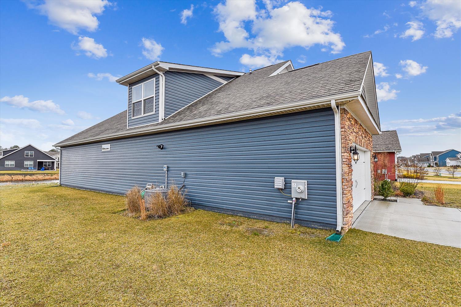 Modern two-story home with blue siding and brick accents in a peaceful neighborhood setting.