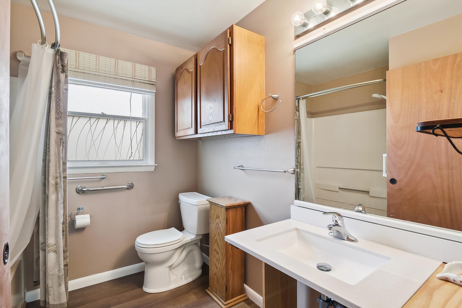 Step into your private bathroom featuring a spacious vanity, well-lit mirror, convenient grab bars, and fresh, practical amenities for your comfort.