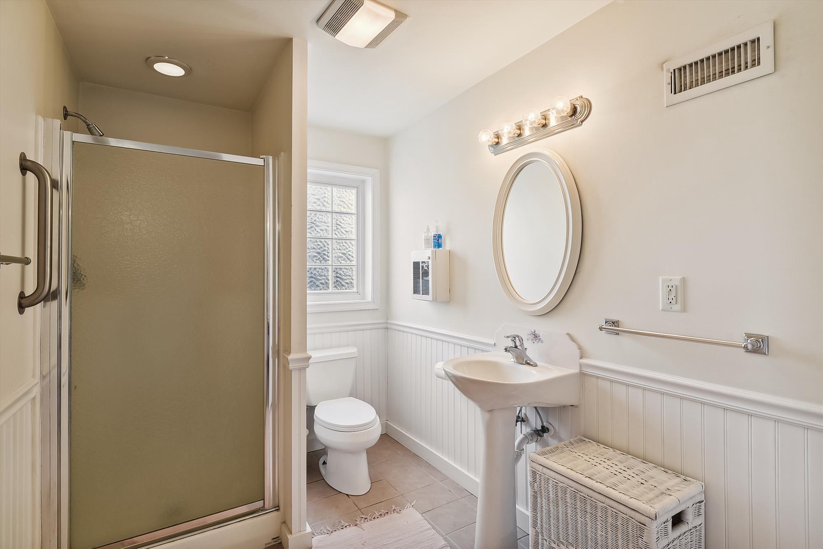 Freshen up in your private bathroom with a spacious walk-in shower, elegant pedestal sink, and plenty of natural light to start your day.