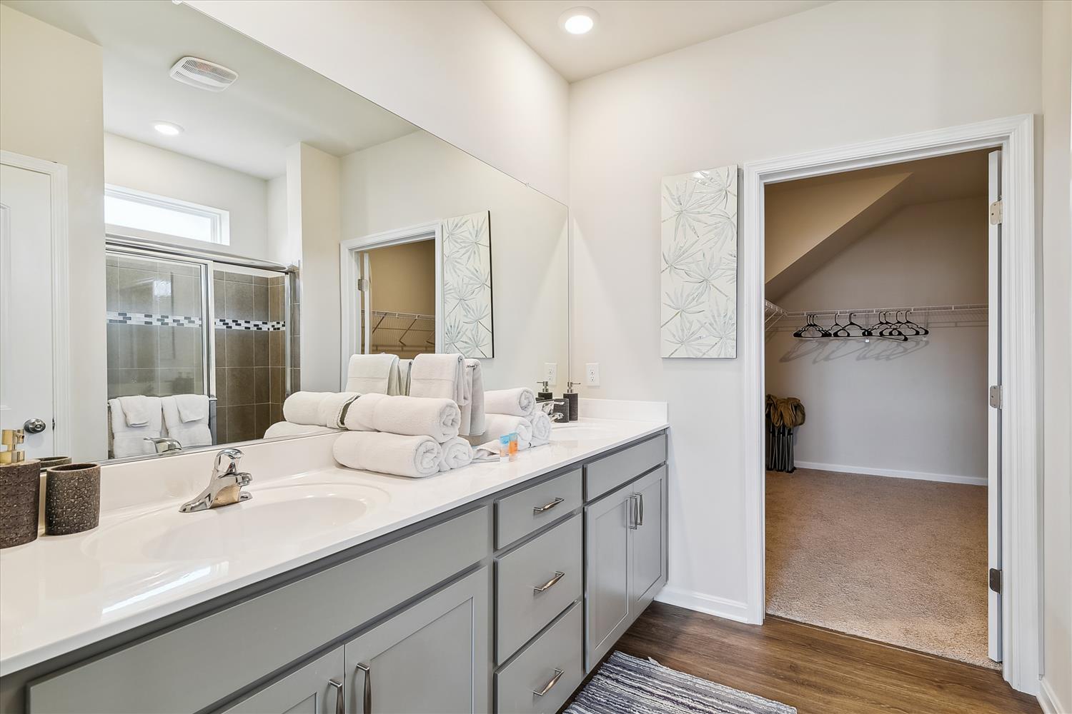 Your spacious master bathroom features dual vanities with pristine countertops, plush towels, and a walk-in closet for effortless organization.