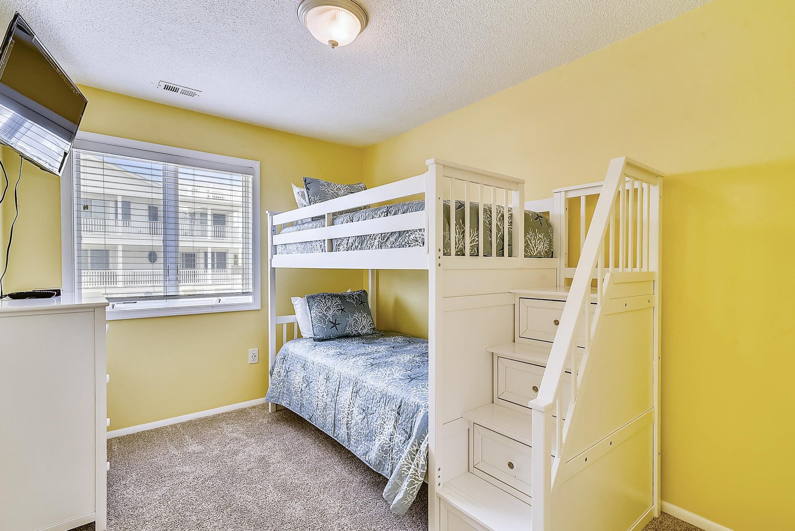 Step into this cheerful bedroom with built-in bunk beds and integrated storage stairs—perfect for gathering at bedtime and making the most of cozy quarters.