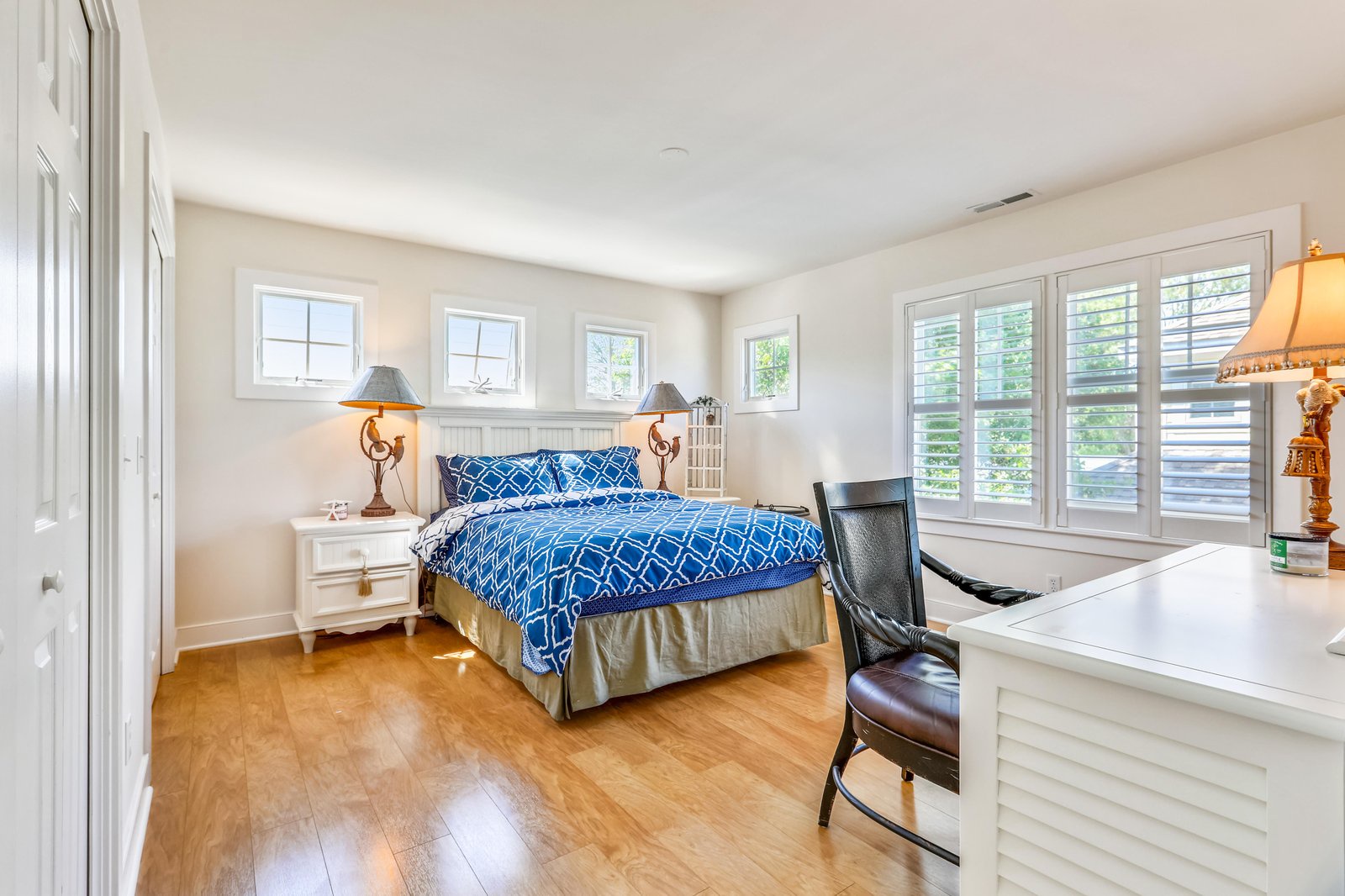 Sink into crisp sheets and wake to soft natural light streaming through white shutters. Your peaceful bedroom awaits with warm wood floors and tasteful coastal accents.