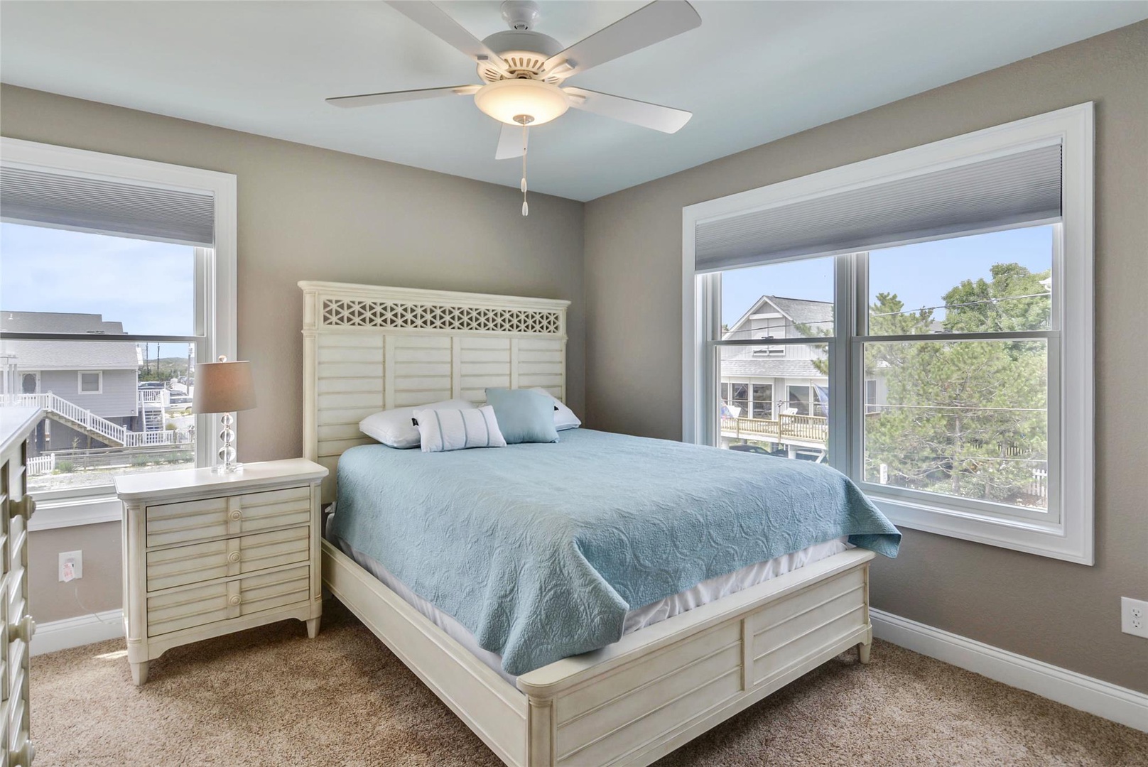 Drift off to sleep in this cozy bedroom with plush carpeting, a ceiling fan, and natural light streaming through dual windows overlooking the neighborhood.