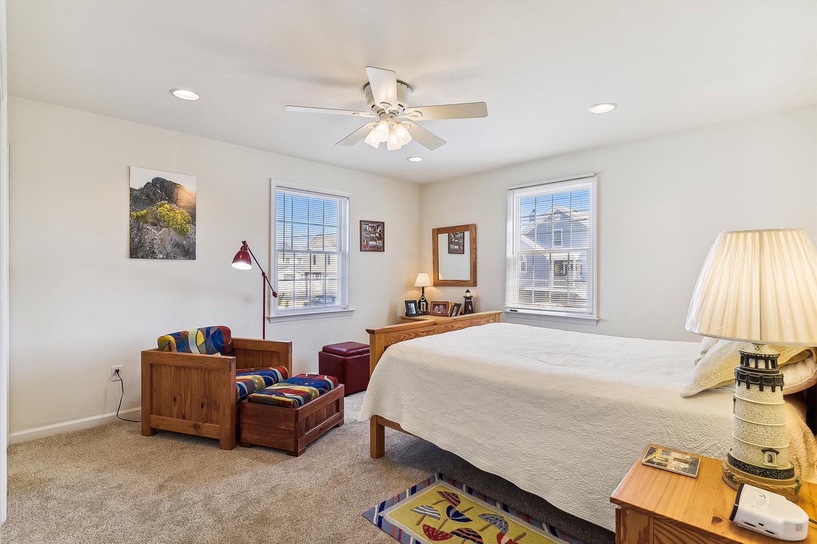 You'll wake refreshed in this airy bedroom with plush carpeting, wood furnishings, and a ceiling fan. Natural light pours through double windows while stylish art and personal touches create a cozy retreat.