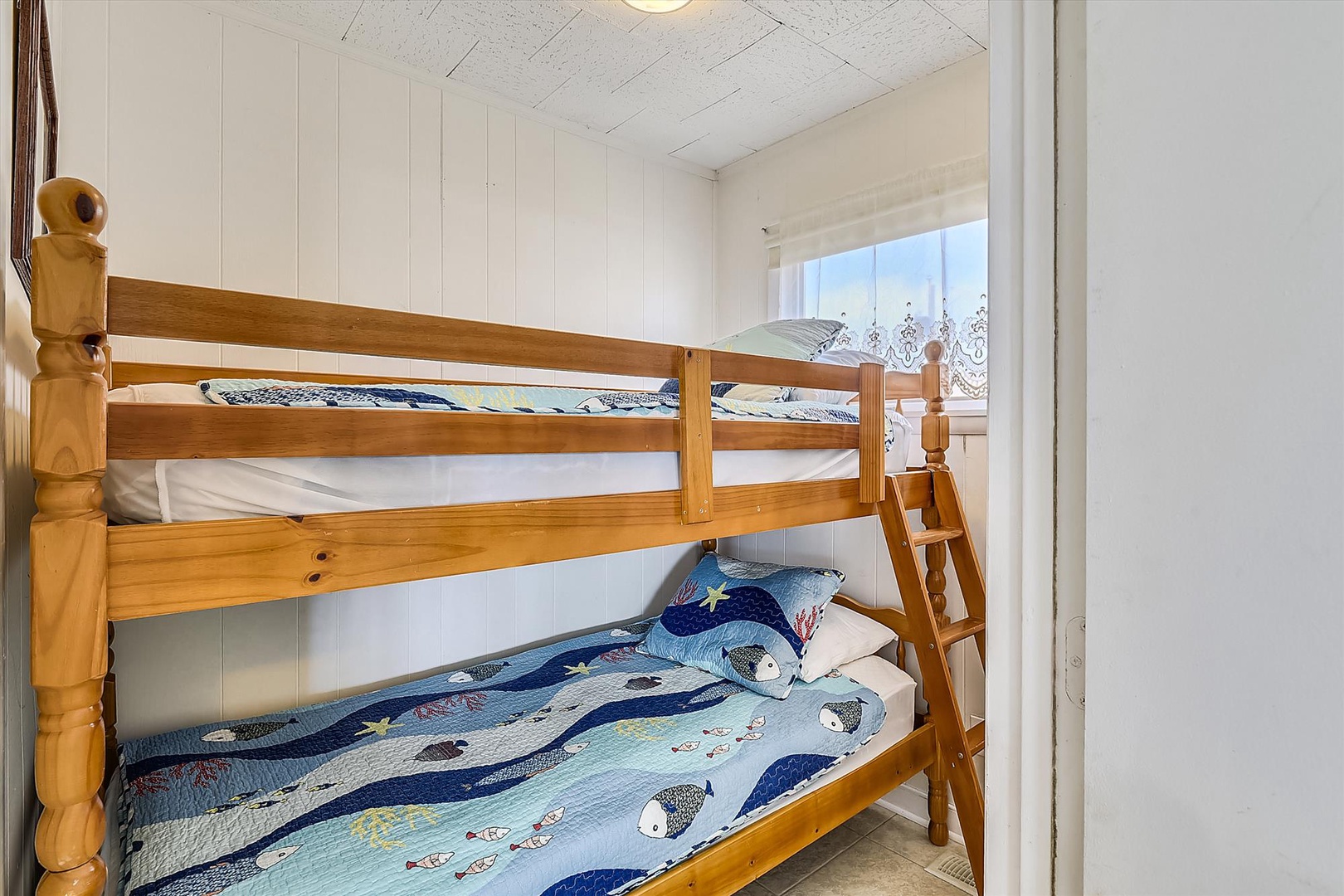 Your kids will love this cheerful bunk room, with sturdy wooden beds and coastal-themed bedding—ideal for sibling adventures and sweet dreams by the sea.