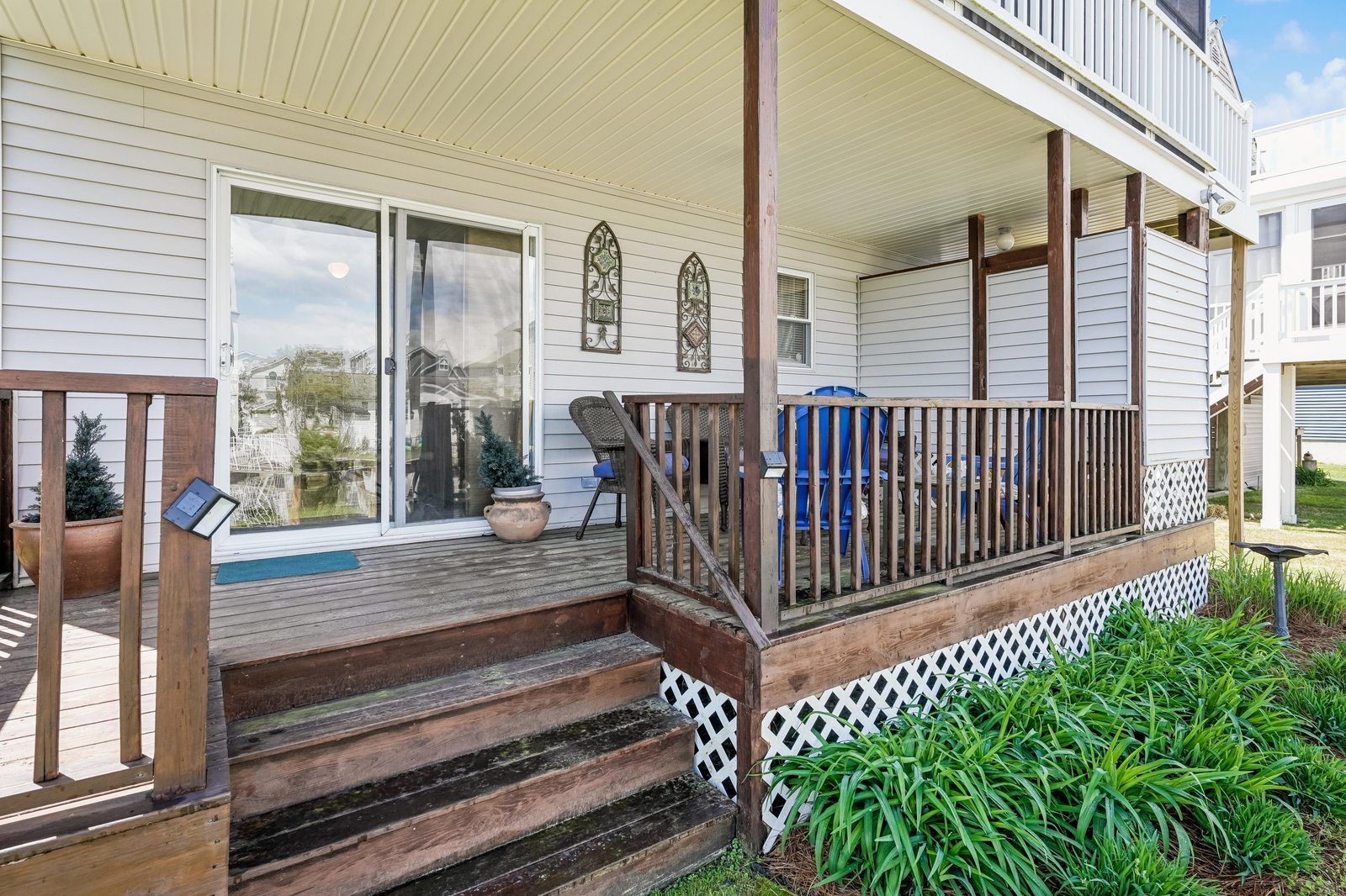 A covered porch with wooden steps and railings welcomes guests to this charming property, featuring decorative accents and serene views of the surrounding neighborhood.