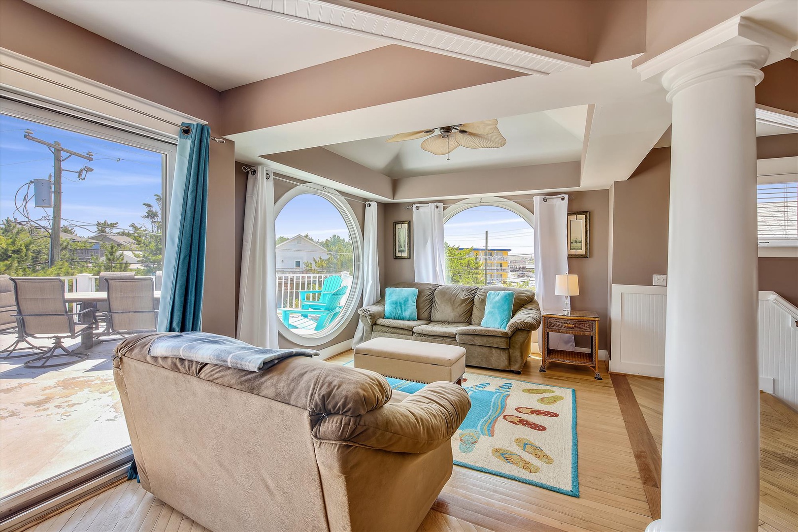 Unwind in your sunlit living space, where turquoise accents and plush seating invite you to relax after beach days, with views of the pool just beyond the arched windows.
