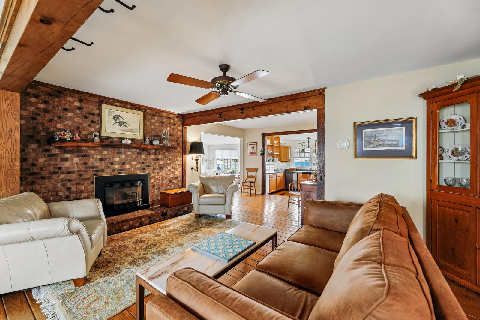 Settle into this warm living room with its cozy brick fireplace and comfortable seating. You'll love the exposed beams and natural wood accents that give the space character.