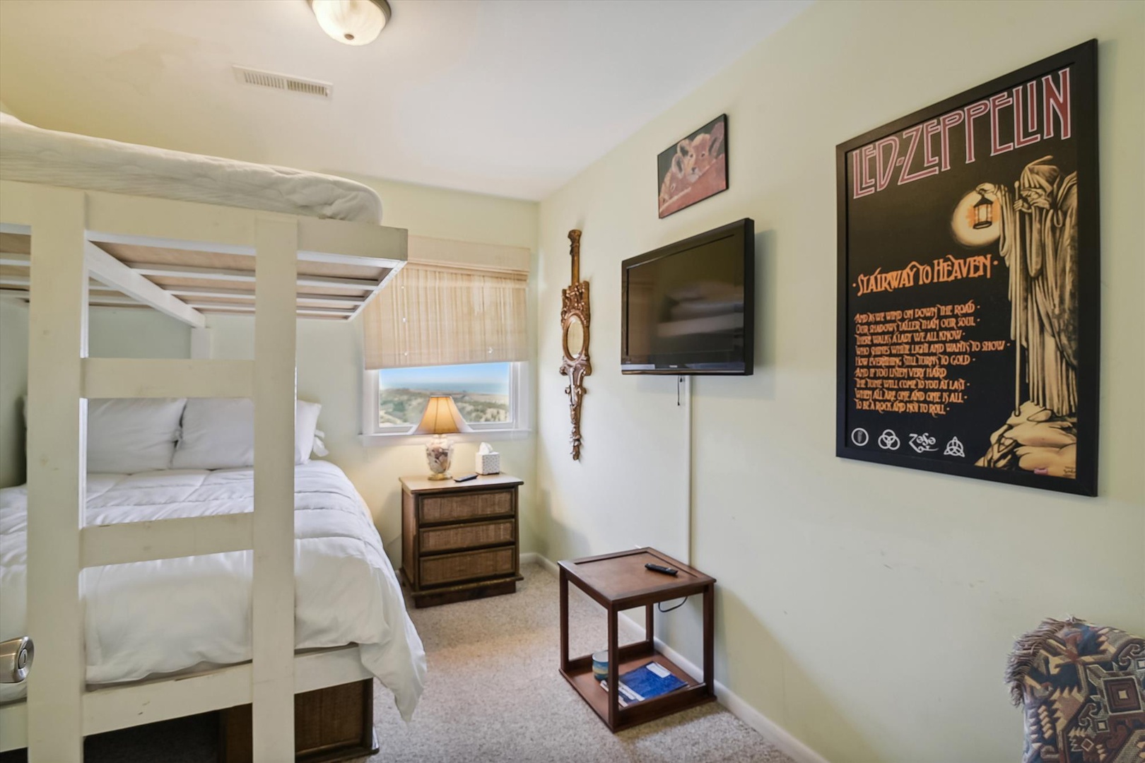 Cozy bunk room with plush bedding, wall-mounted TV, and cool rock memorabilia creates your perfect retreat after a fun day exploring.