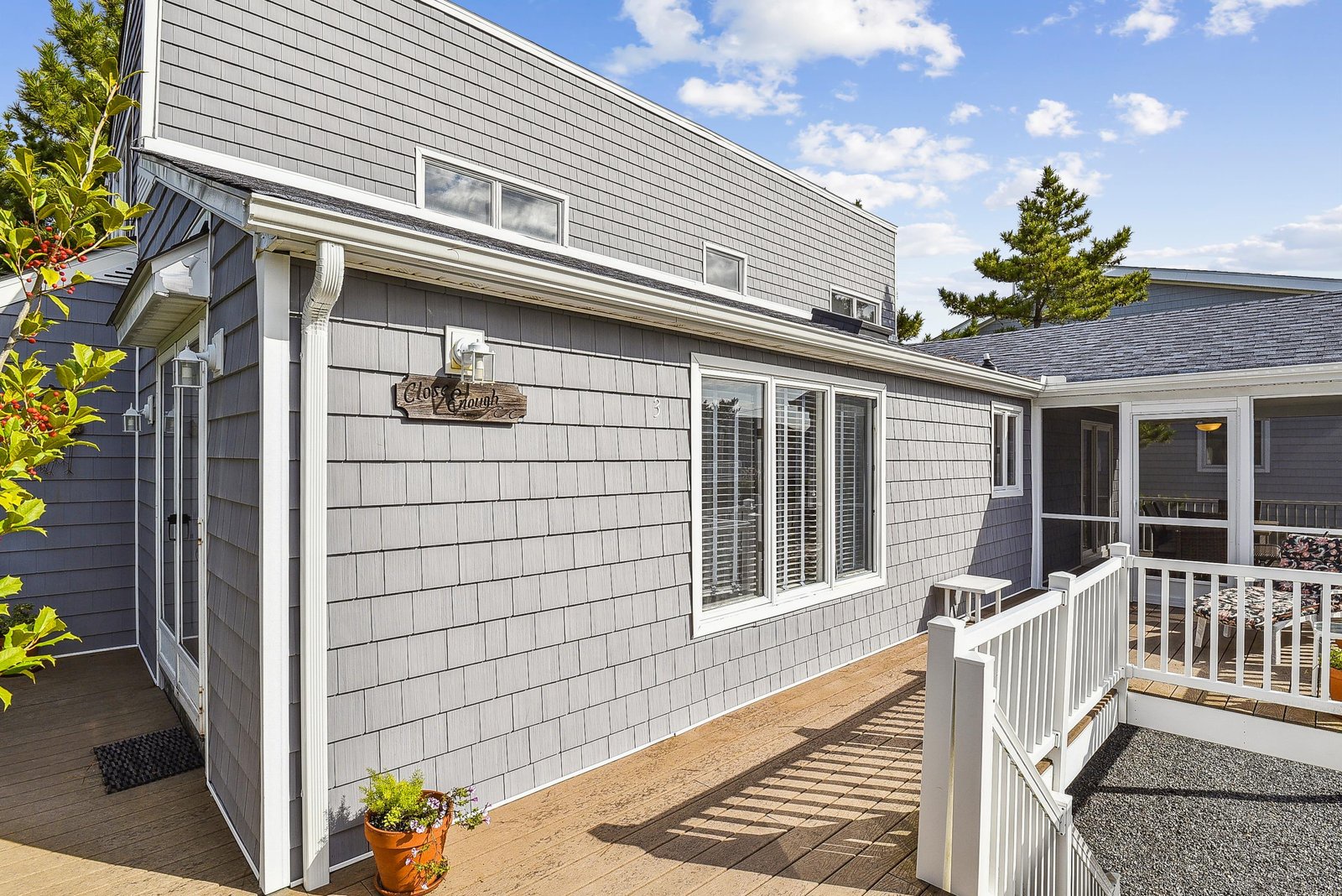 The property features classic coastal architecture with shingled siding and welcoming outdoor spaces, set under open blue skies.