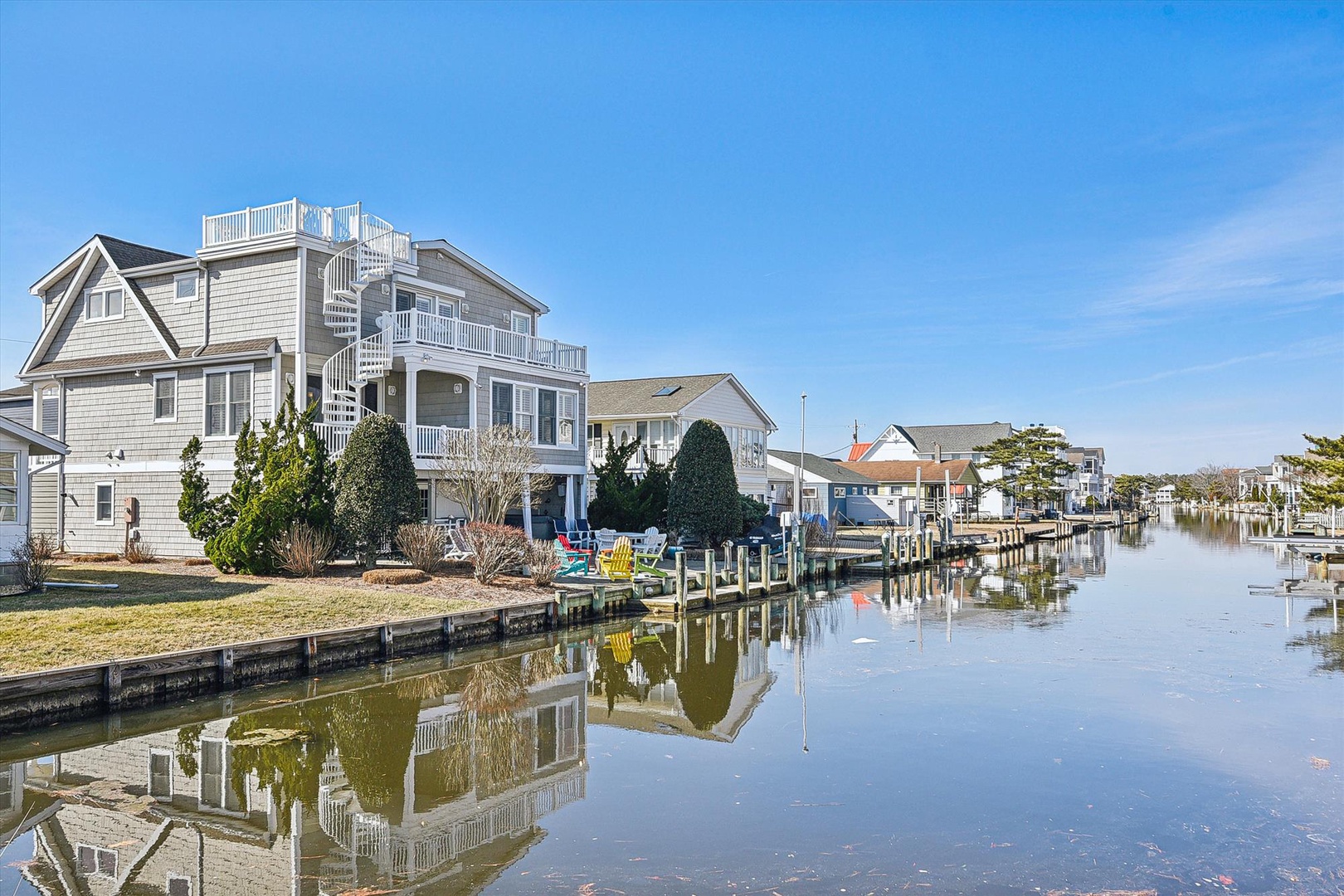 Waterfront property nestled along a tranquil canal with private dock access and rooftop deck, surrounded by peaceful residential homes in a scenic coastal neighborhood.