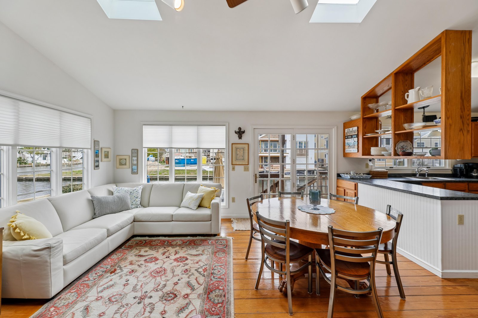 Unwind in your bright, open living and dining space where skylights pour in natural light and windows frame waterfront views—perfect for morning coffee or cozy evenings after exploring the coast.