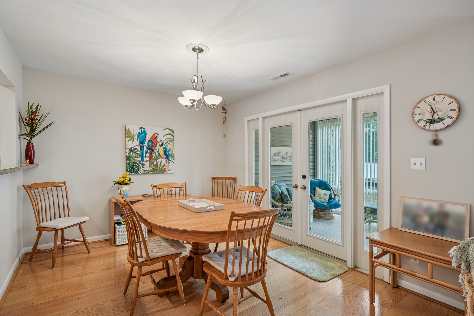 Gather around your beautiful wooden dining table where meals become memories, with cheerful tropical art and French doors opening to your private patio.