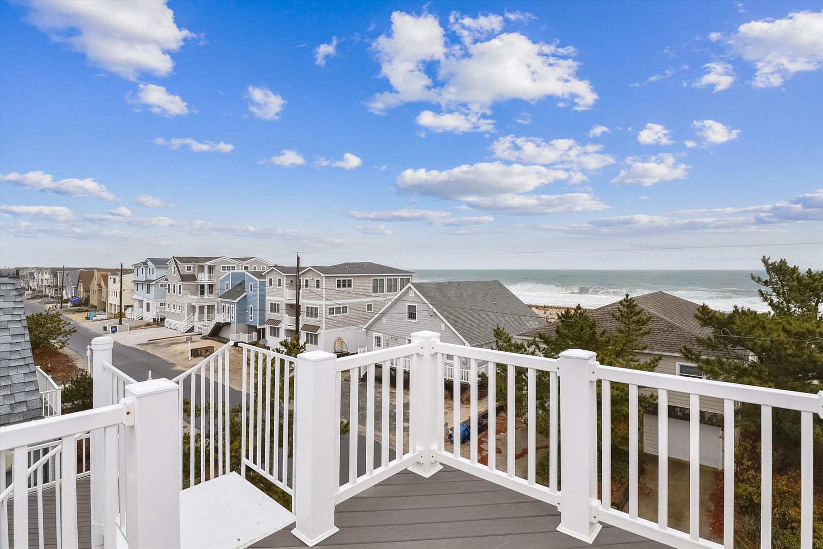 Elevated balcony deck offers sweeping views of the oceanfront neighborhood and coastal horizon. The property sits near the beach in a scenic residential area.
