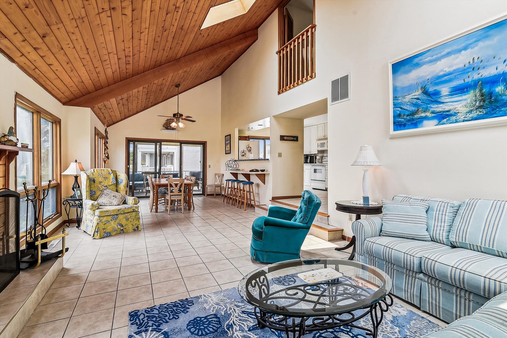 Relax in this bright, open living space where high vaulted ceilings and coastal decor create an airy, beachy vibe. Stretch out on the sofa, enjoy natural light, and feel at home in this welcoming retreat.