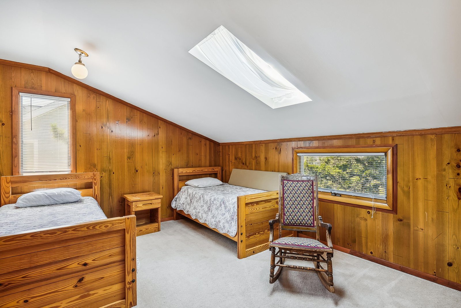 Wake up to natural light pouring through the skylight above your cozy, wood-paneled retreat. This warm bedroom offers two comfortable beds and a peaceful spot to start your mornings right.