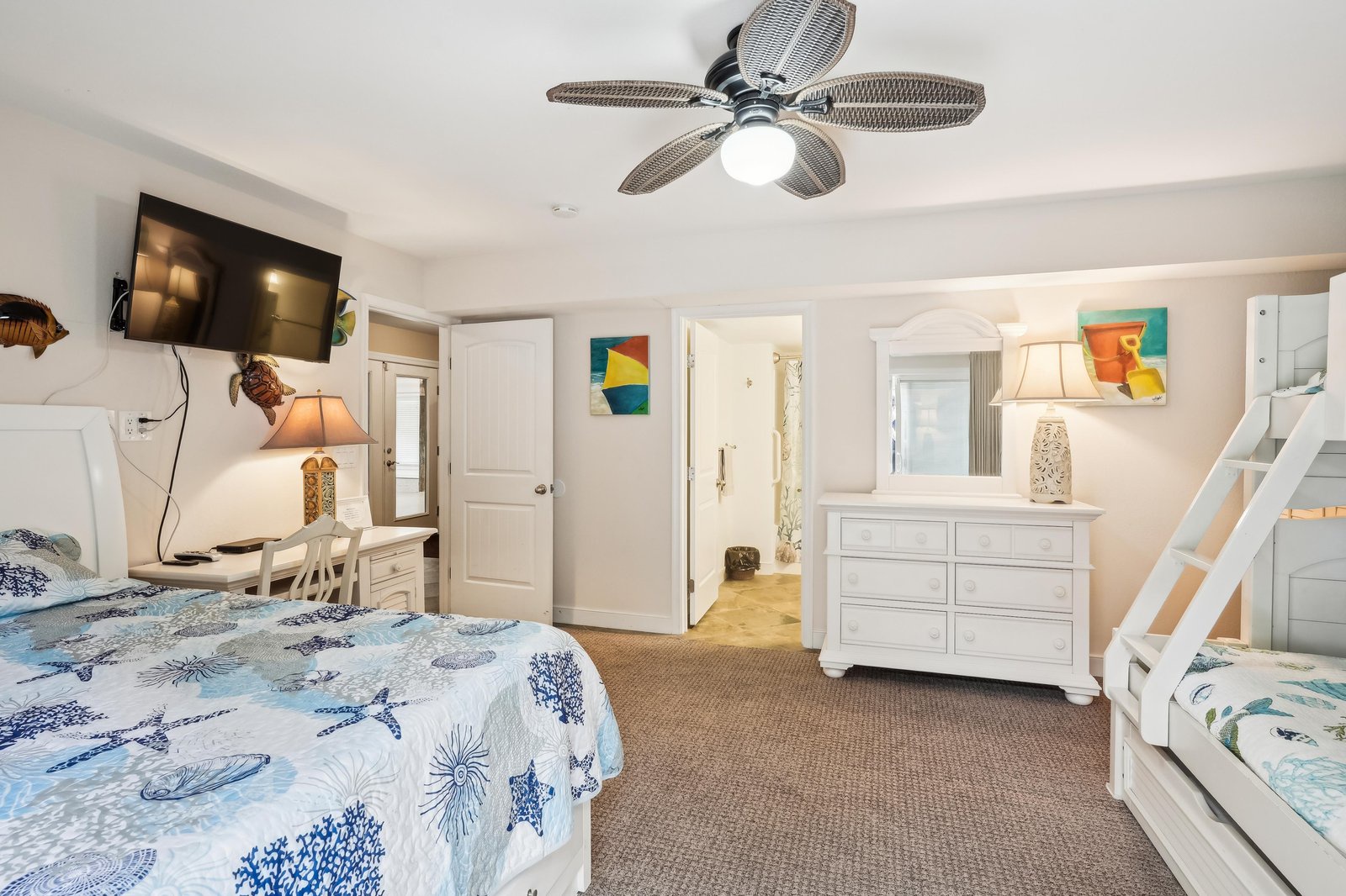 Settle into your bright coastal bedroom, where ocean-themed bedding and cheerful beach art set a relaxing tone. A ceiling fan keeps you cool while colorful touches invite restful nights.