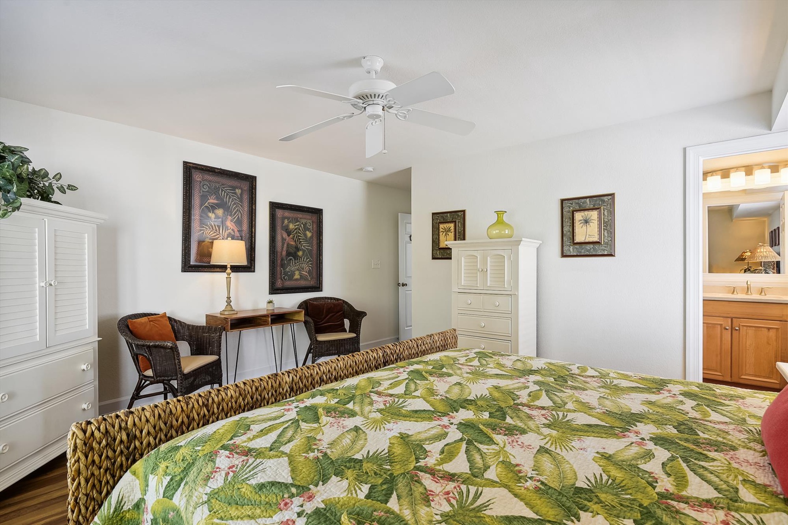 Bright, breezy bedroom with tropical flair—relax under the fan, sink into the inviting bed, and enjoy a cozy seating nook perfect for morning coffee or a good book.