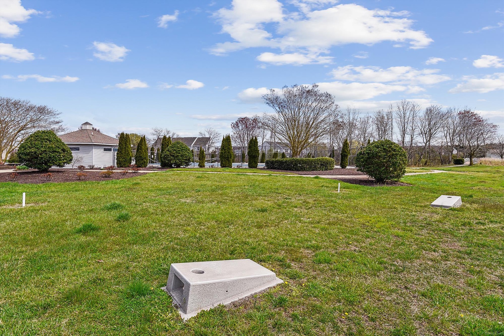 Spacious lawn area framed by mature trees and landscaping, offering an open recreational space during your stay at this peaceful property.