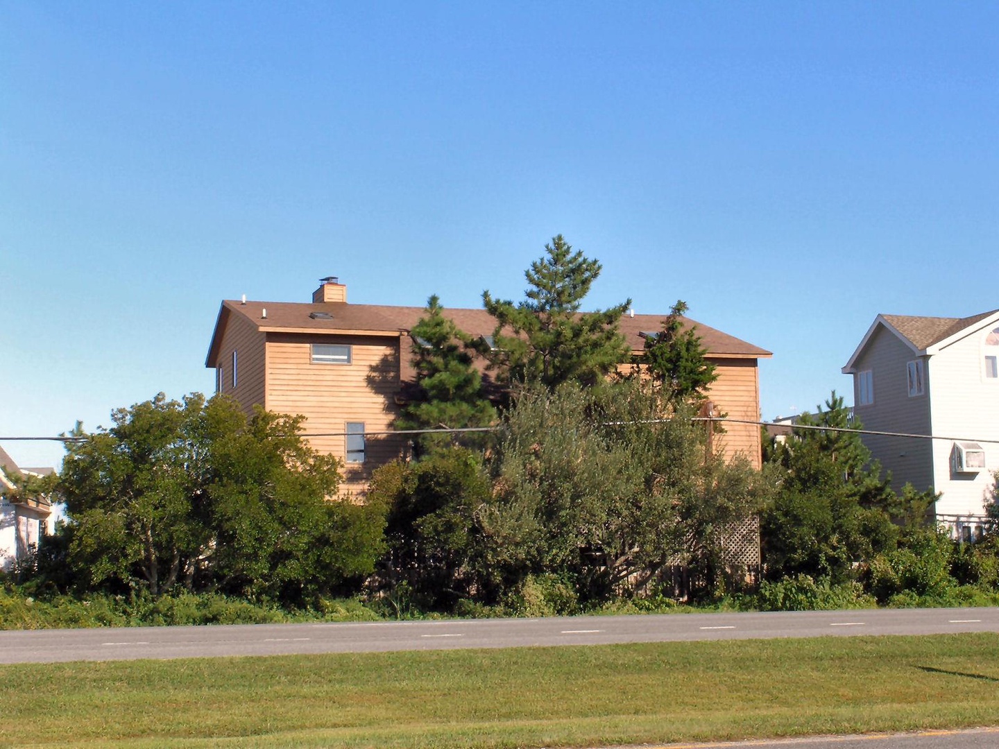 A residential property situated in a quiet neighborhood, surrounded by mature trees and landscaping, with nearby homes creating a peaceful residential setting.