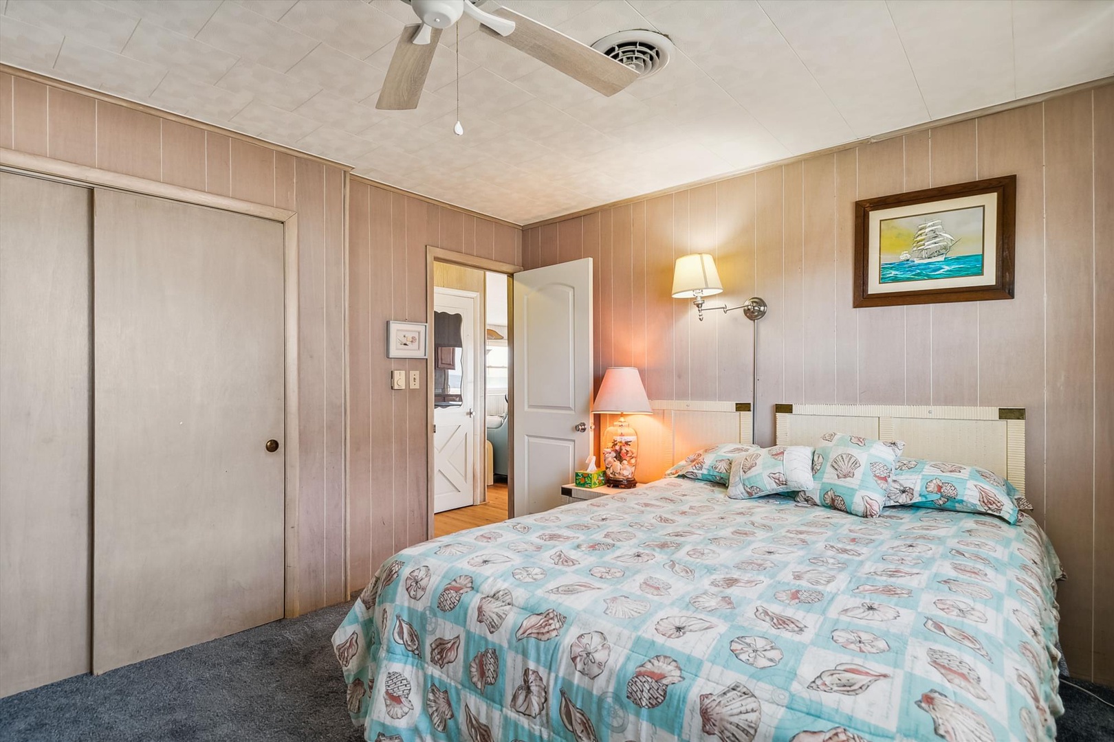 Slip into this cozy coastal bedroom with nautical charm, soft lighting, and a ceiling fan to keep your nights cool and comfortable.