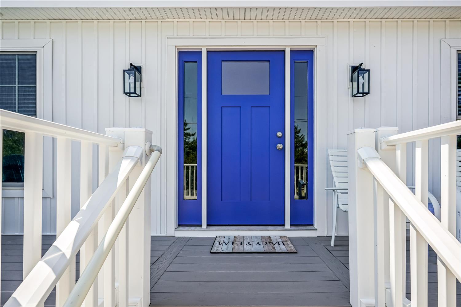 A bright blue front door welcomes you to this coastal-style rental, framed by white siding and classic lanterns. The charming porch sets a cheerful, inviting tone from the moment you arrive.