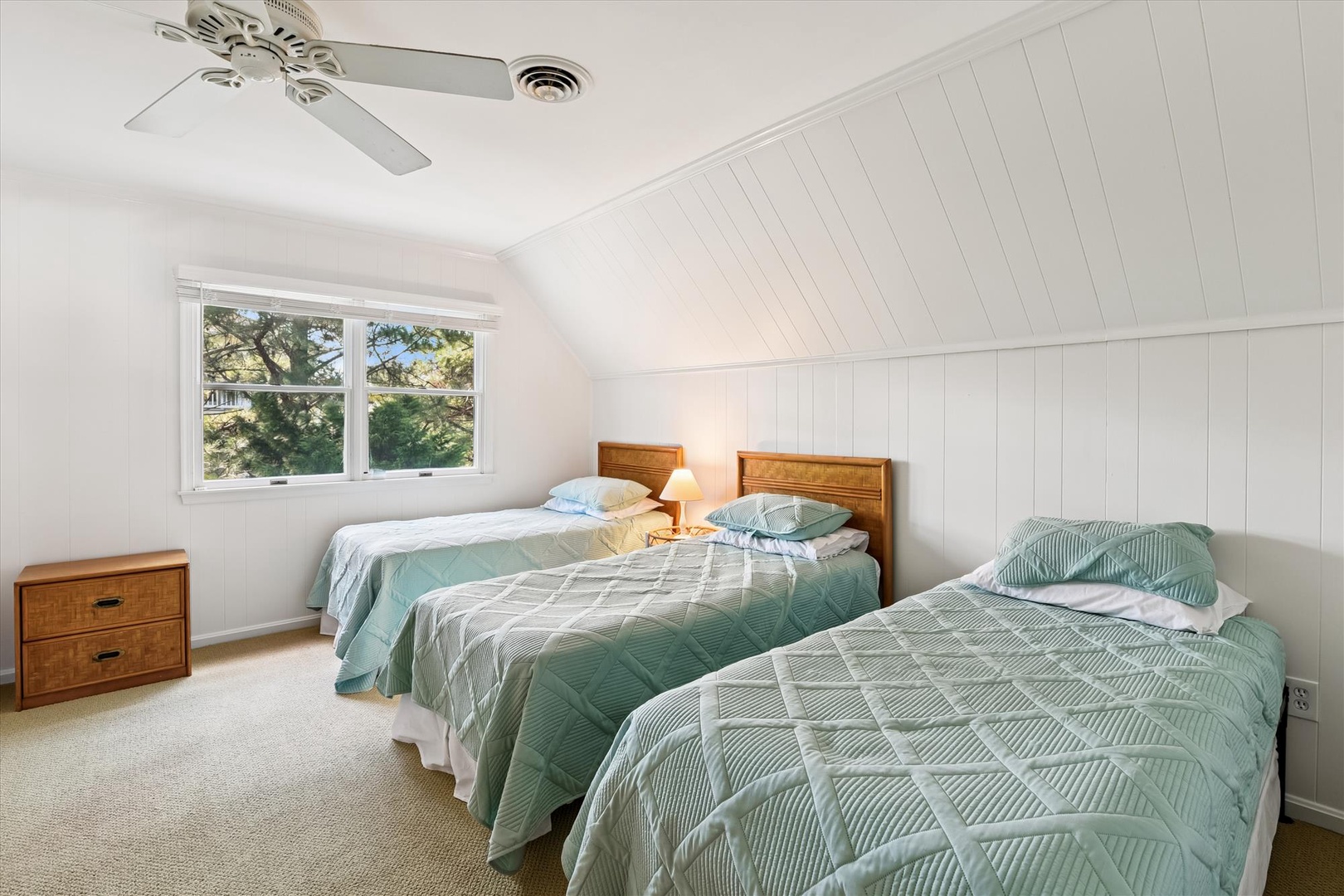 Rest easy in this bright, airy bedroom where two comfortable beds await beneath charming slanted ceilings and gentle natural light.