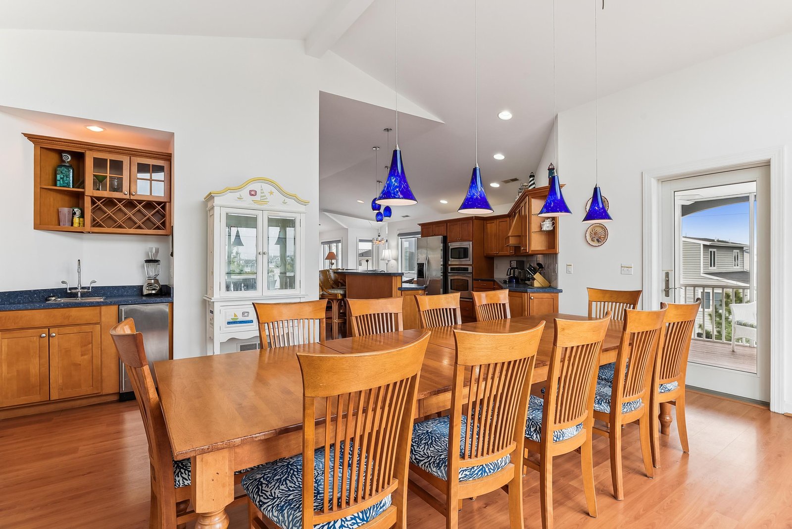 Gather around the inviting dining table, warmed by rich wood finishes and sparkling blue pendant lights that set a welcoming tone for your meals together.