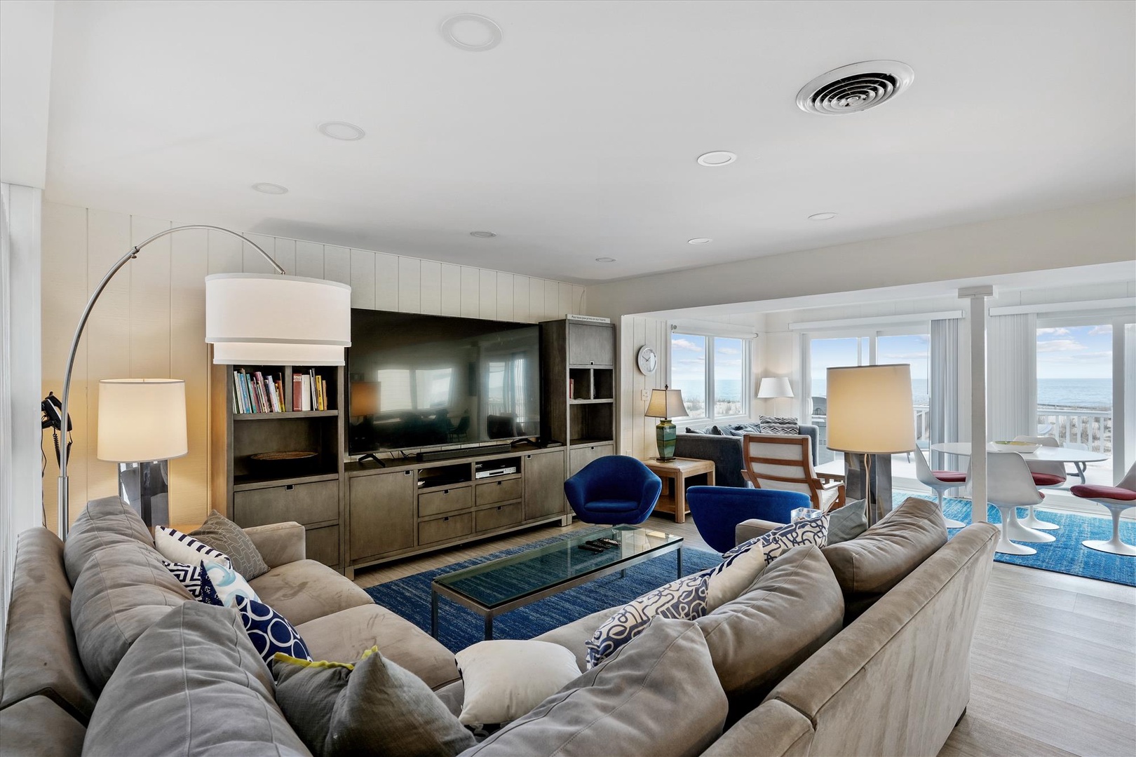 Sink into plush seating and enjoy your favorite shows on the large flat-screen TV, while natural light streams through expansive windows overlooking the ocean. This inviting space blends comfort and coastal elegance perfectly.